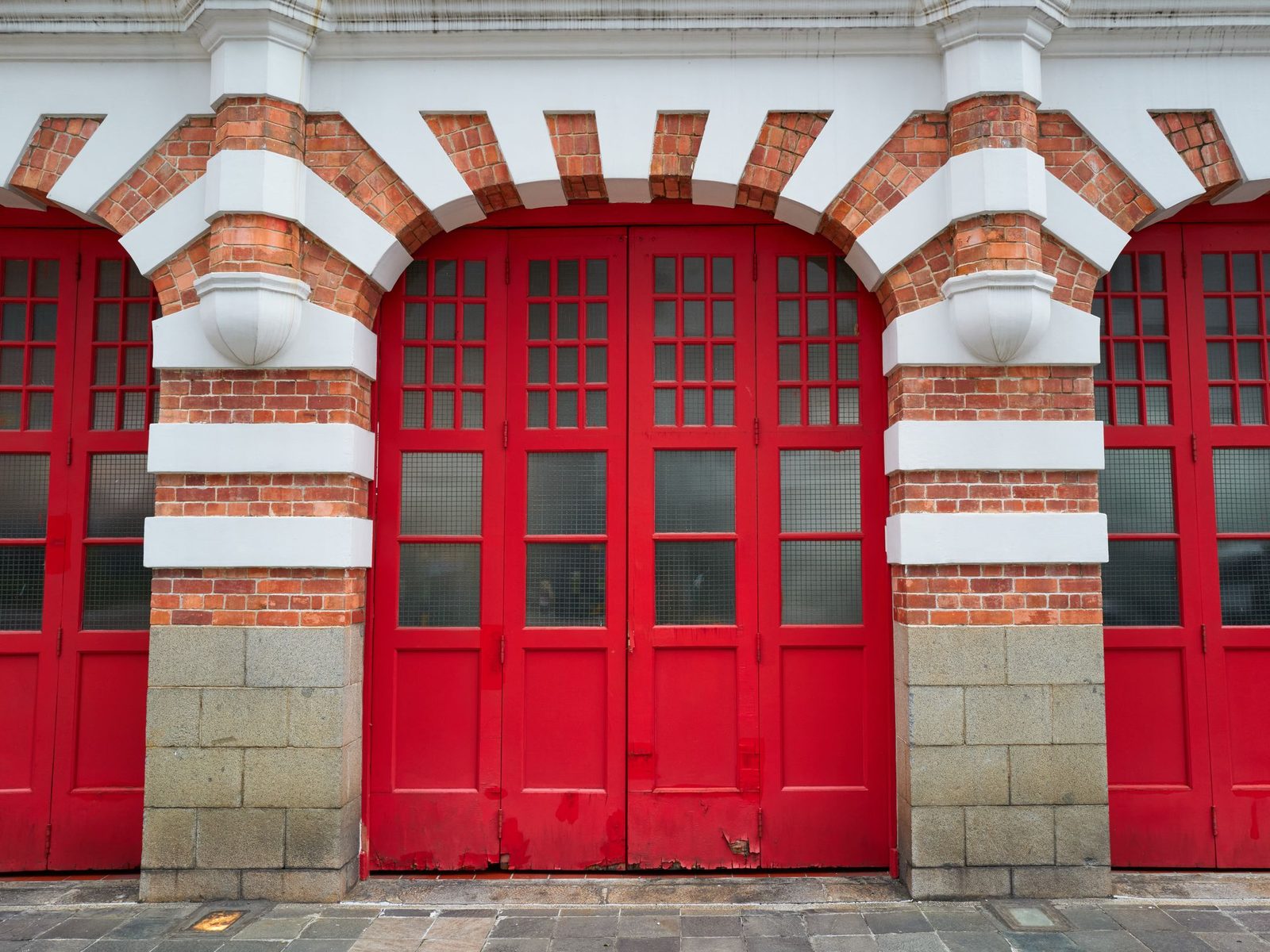 Red folding doors under brick arches with white bands